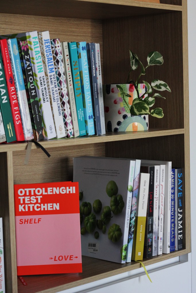 Bookshelves with a variety of cookbooks, and OTK Shelf Love facing towards the camera.
