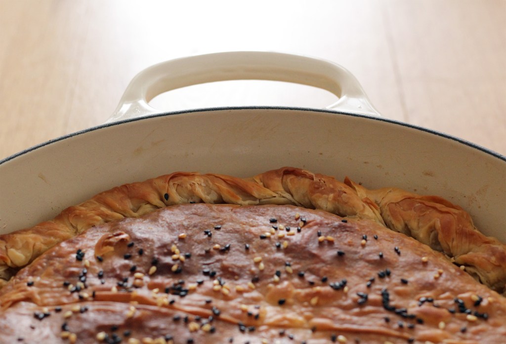 Image shows a close-up of a golden brown pie top and crust in a round baking dish.